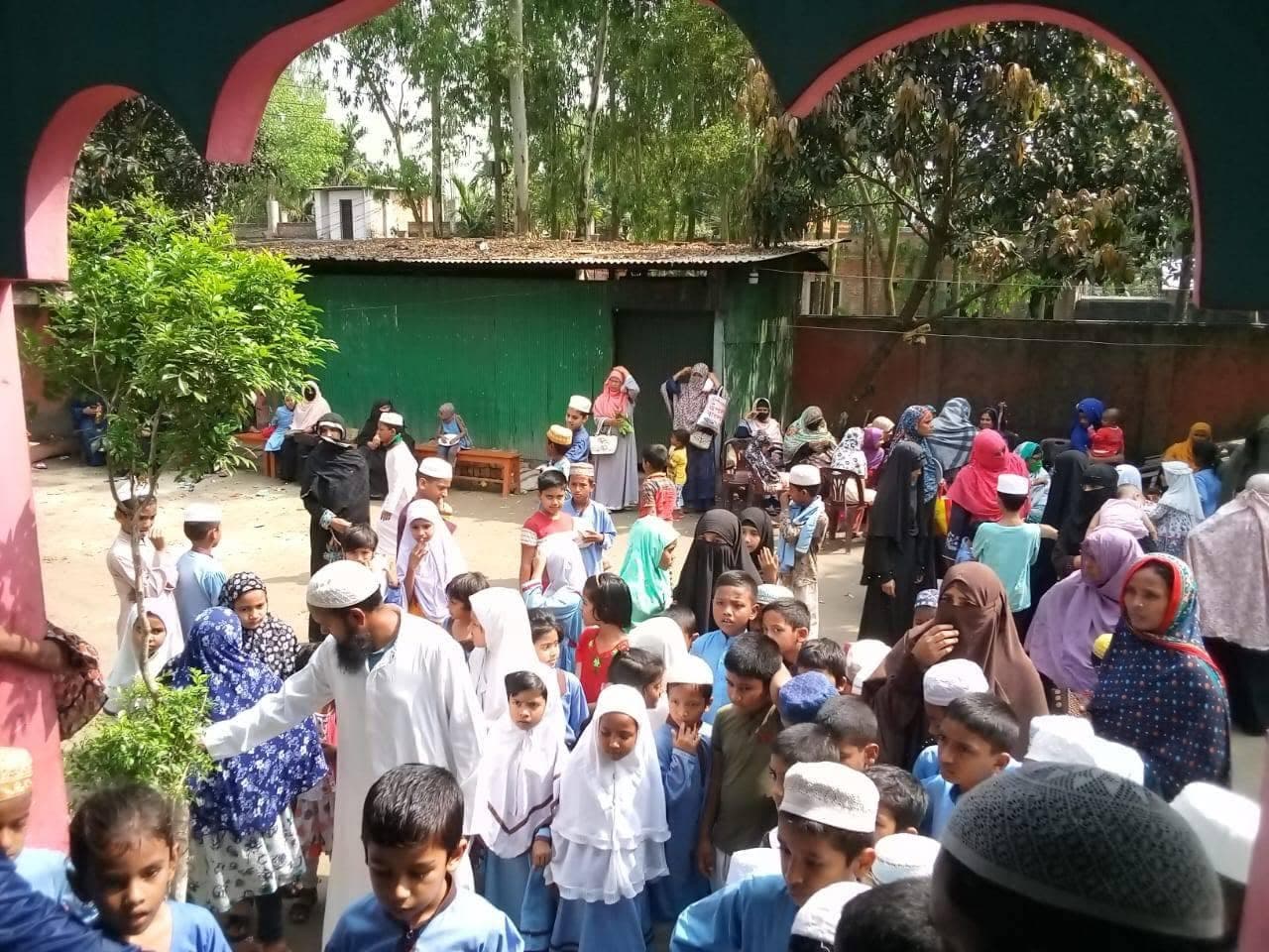 খিলানযুক্ত ফটকের পাশে ক্যাম্পাস প্রাঙ্গণে জড়ো হওয়া শিক্ষার্থী ও অভিভাবকগণ
